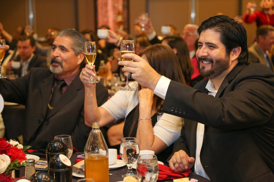 A group of people are sitting at a table toasting with champagne glasses.