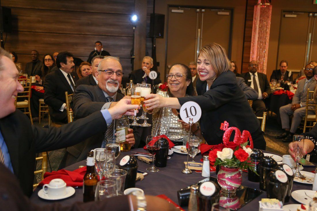 A group of people are sitting at a table toasting with wine glasses.