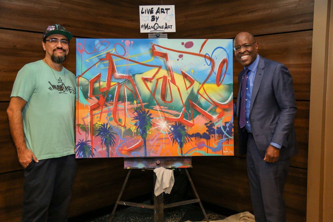 Two men are standing next to a large painting on an easel.