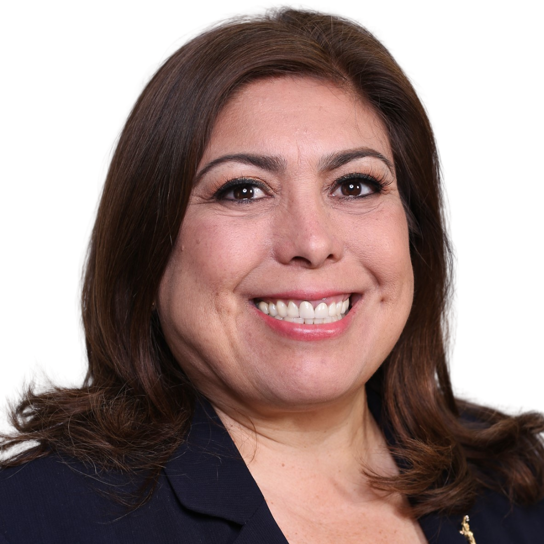 A woman wearing a pink shirt and a black jacket smiles for the camera