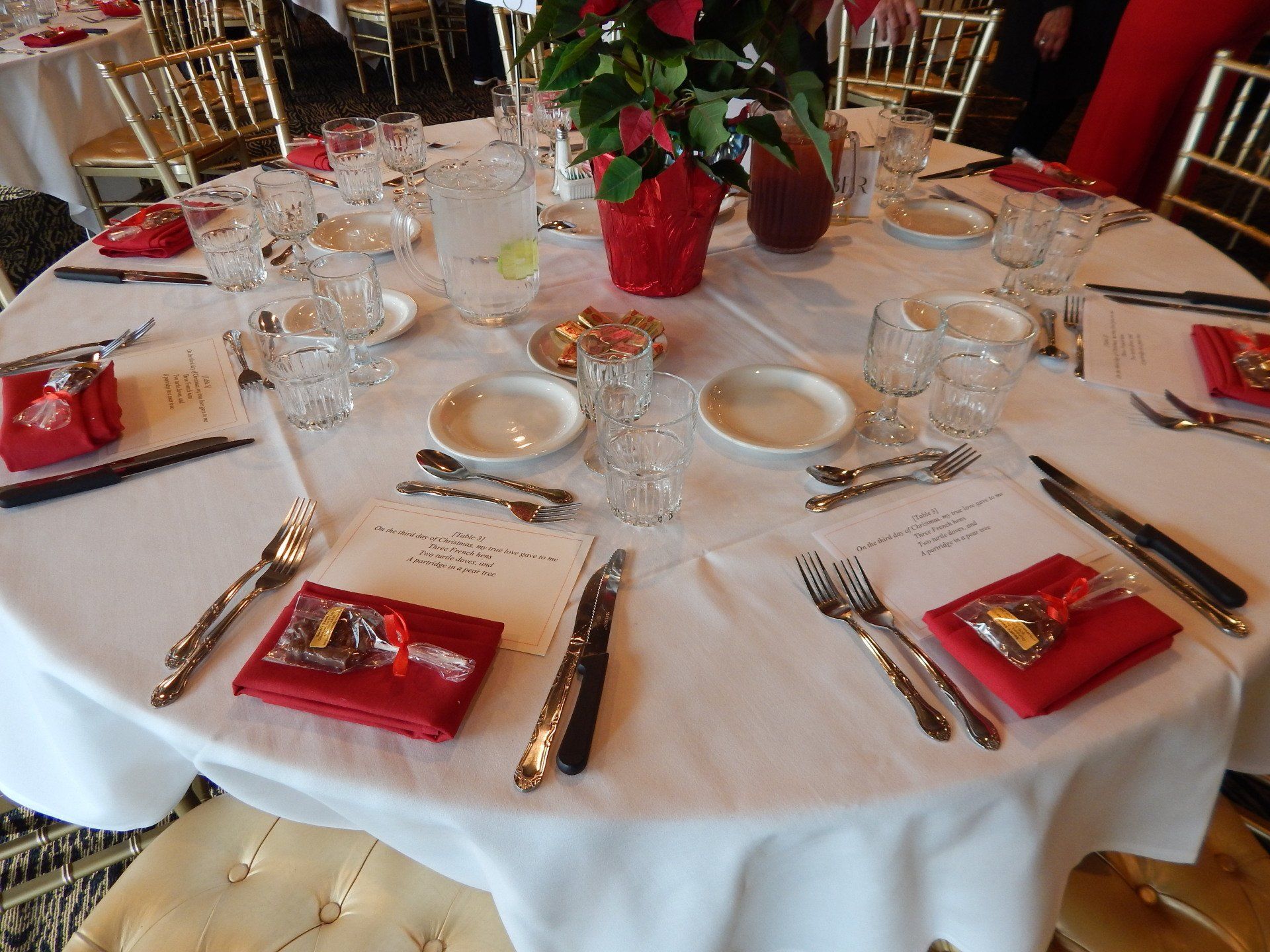 A round table with a white table cloth and red napkins