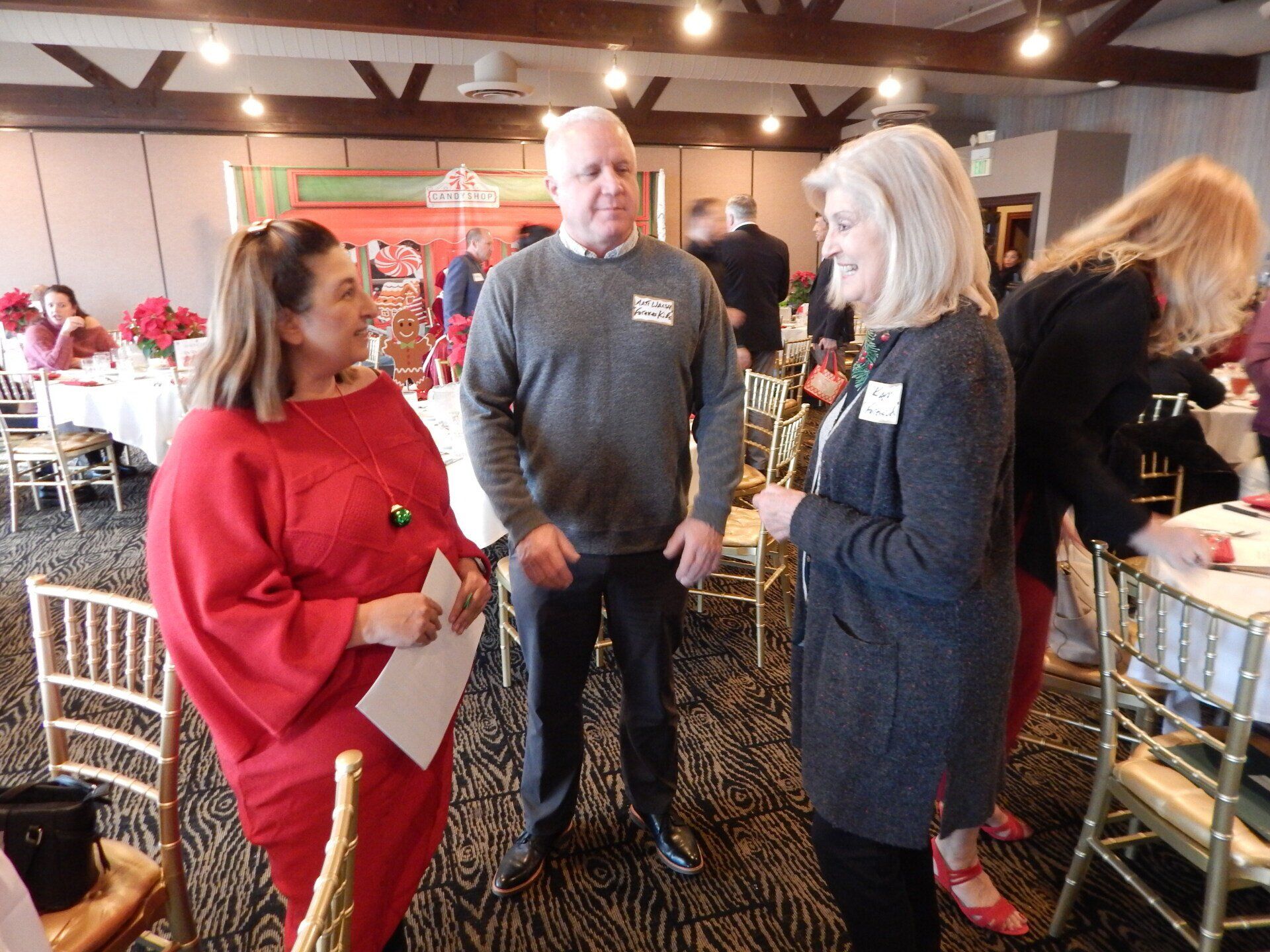 A group of people are standing in a room talking to each other.