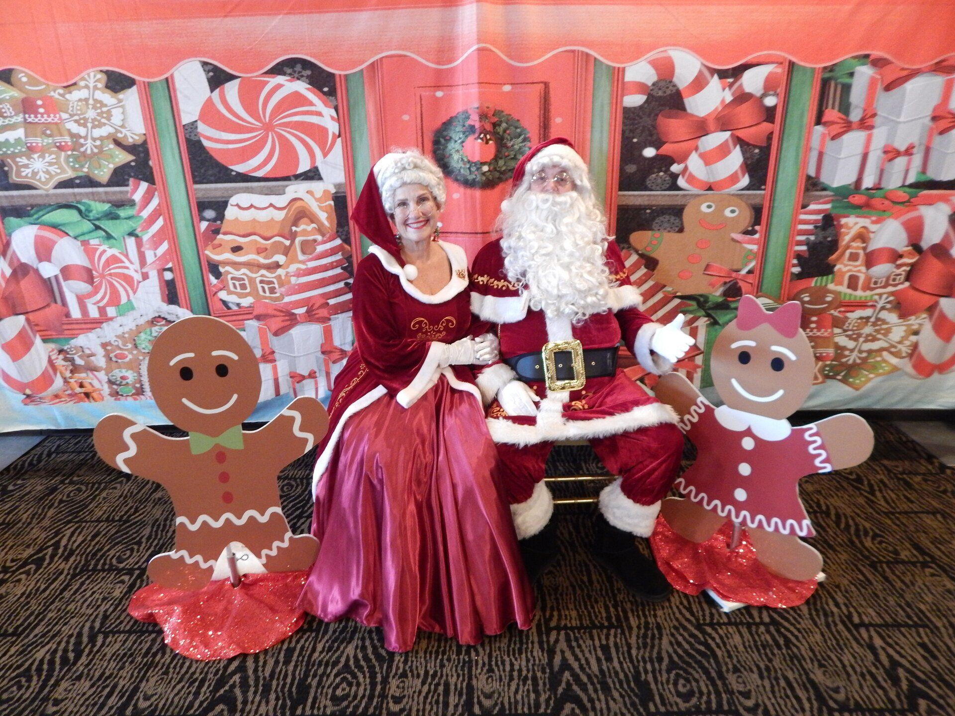 A man and a woman dressed as santa claus and gingerbread men are posing for a picture.