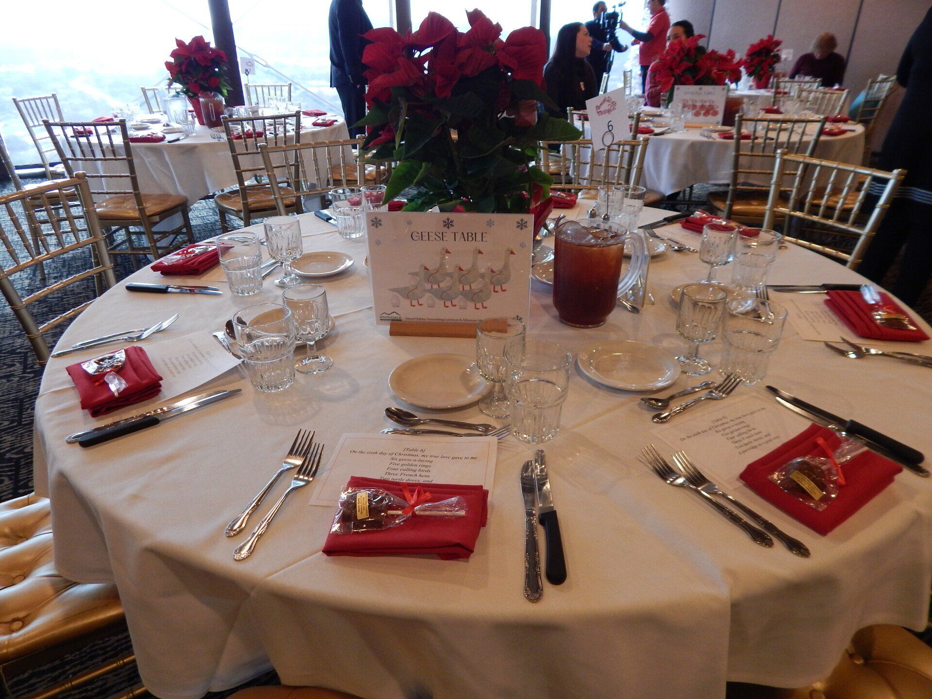 A round table with a white table cloth and red napkins