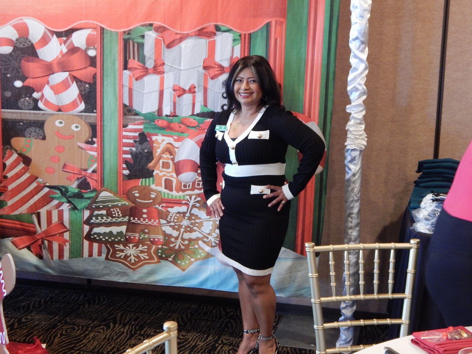 A woman in a black and white dress is standing in front of a christmas backdrop