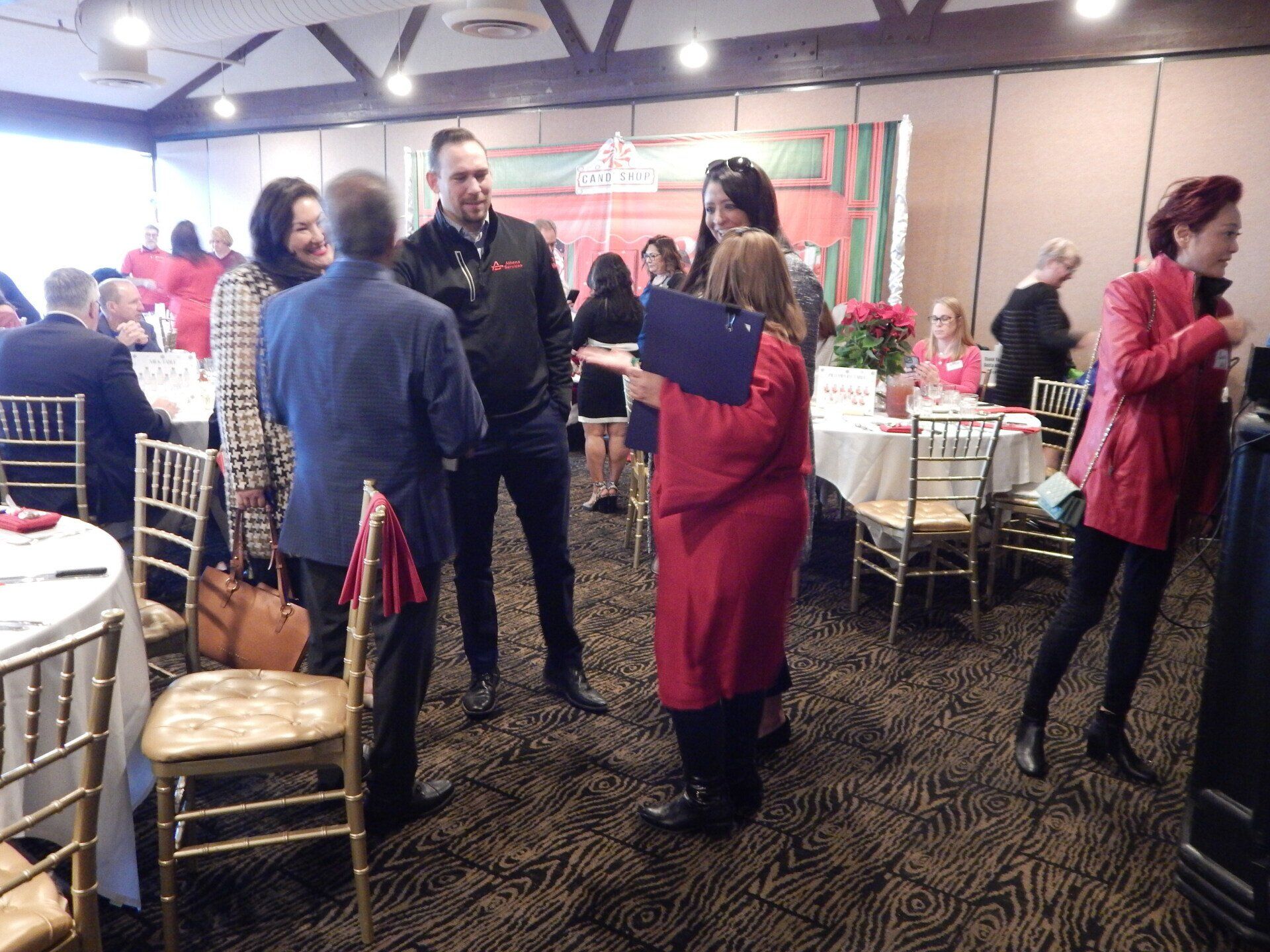 A group of people are standing in a room with tables and chairs.