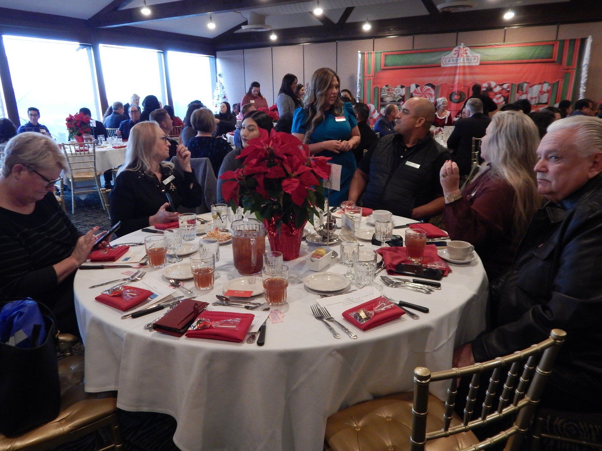 A group of people are sitting around a table with a poinsettia on it.