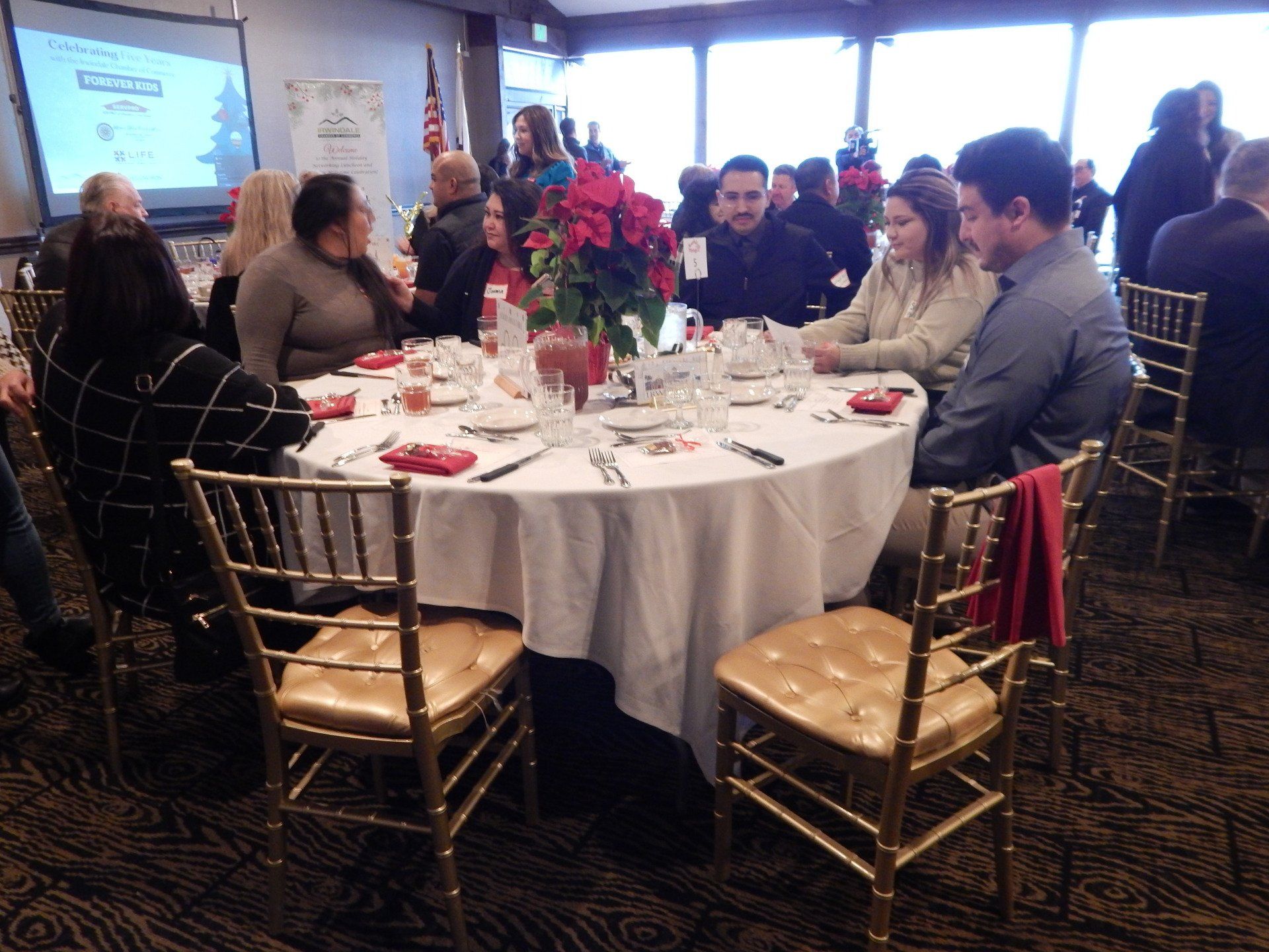 A group of people are sitting around a table with a white table cloth