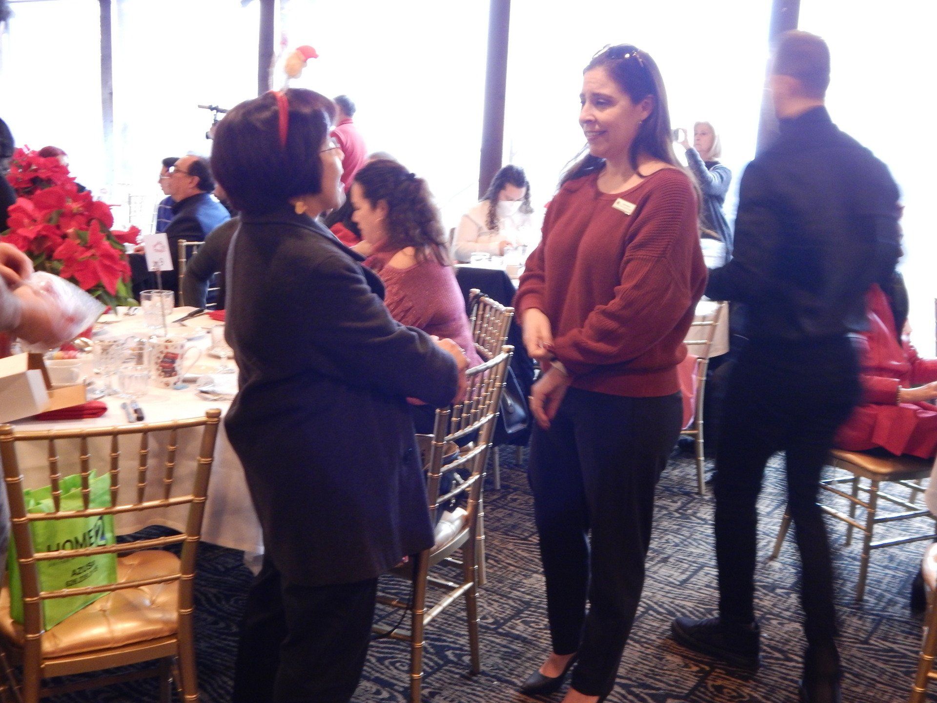 A group of people are standing in a room talking to each other.