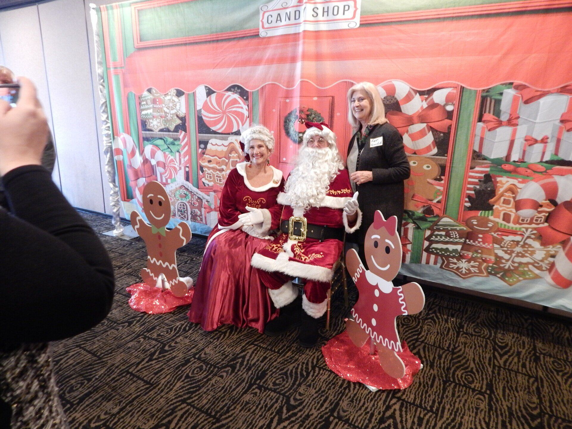 A woman is taking a picture of santa claus and two gingerbread men.