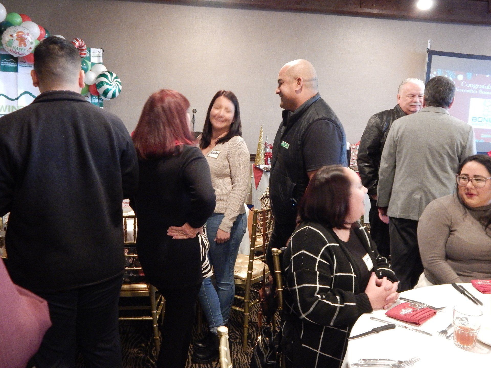 A group of people are standing in a room talking to each other.