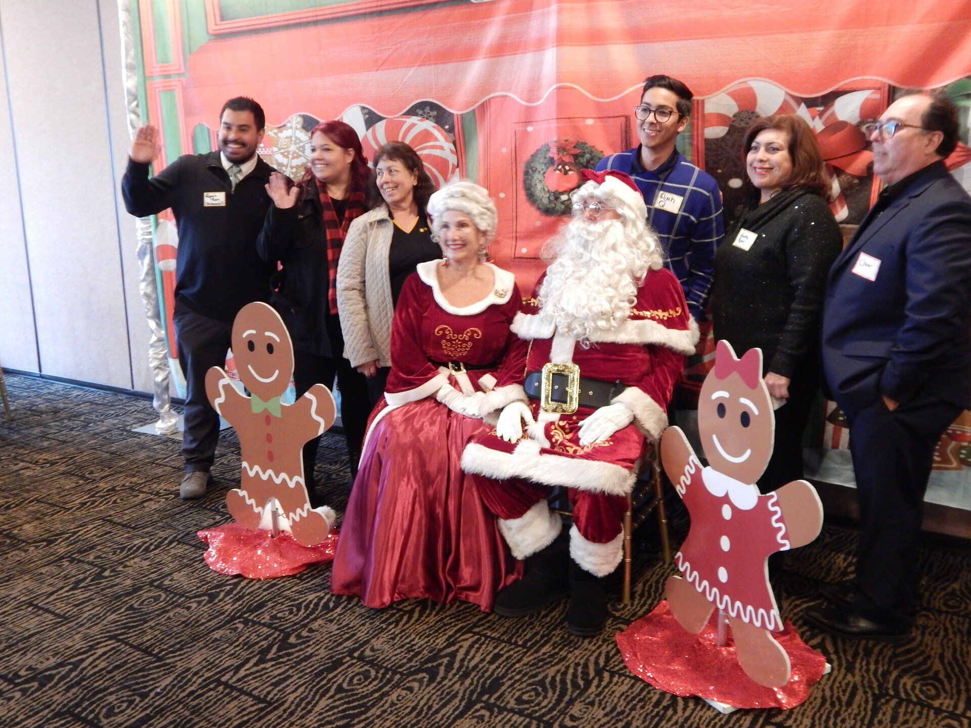 A group of people are posing for a picture with santa claus and gingerbread men.
