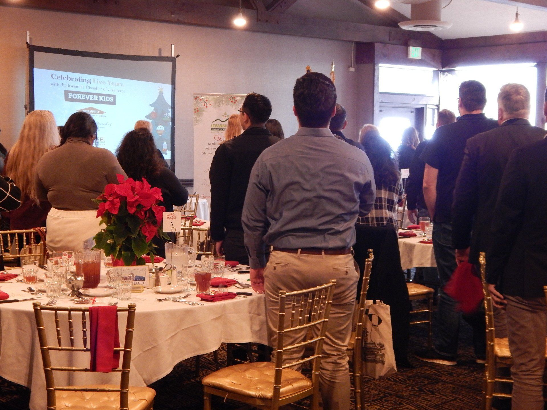 A group of people are gathered in a room with tables and chairs