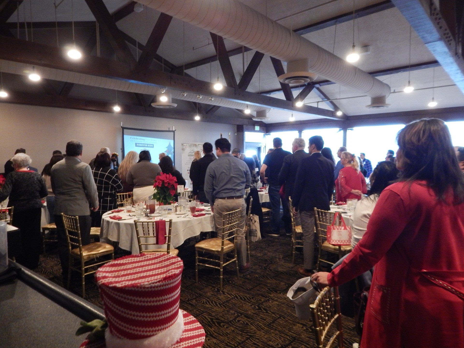 A group of people are standing around tables in a large room.