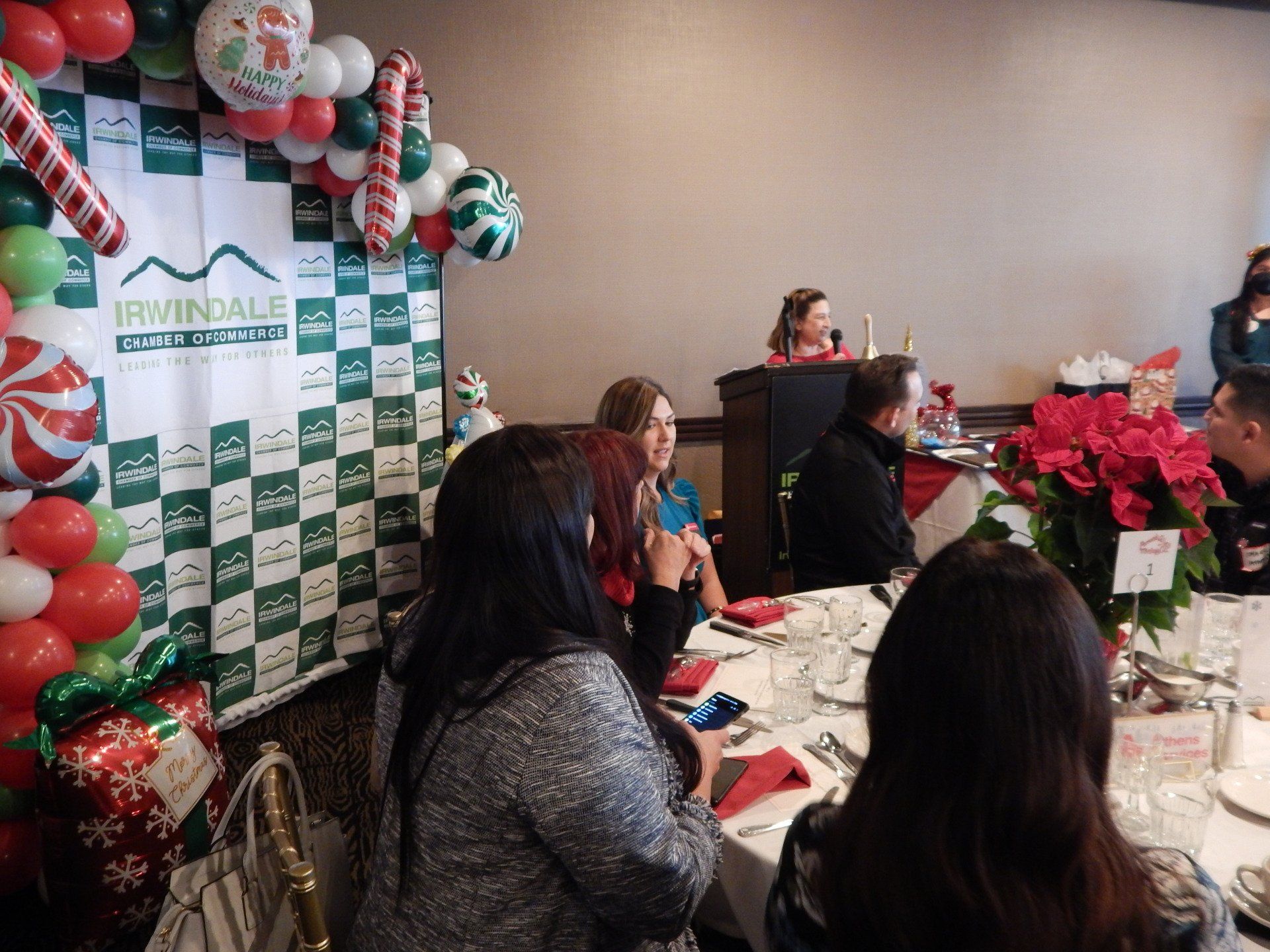 A group of people are sitting at tables in a room decorated for christmas.