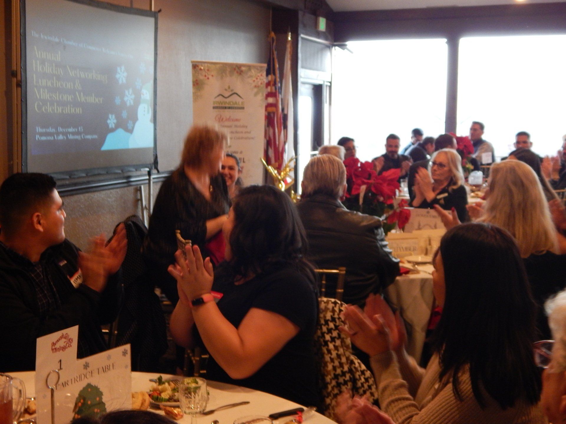 A group of people sitting at tables in front of a projector screen