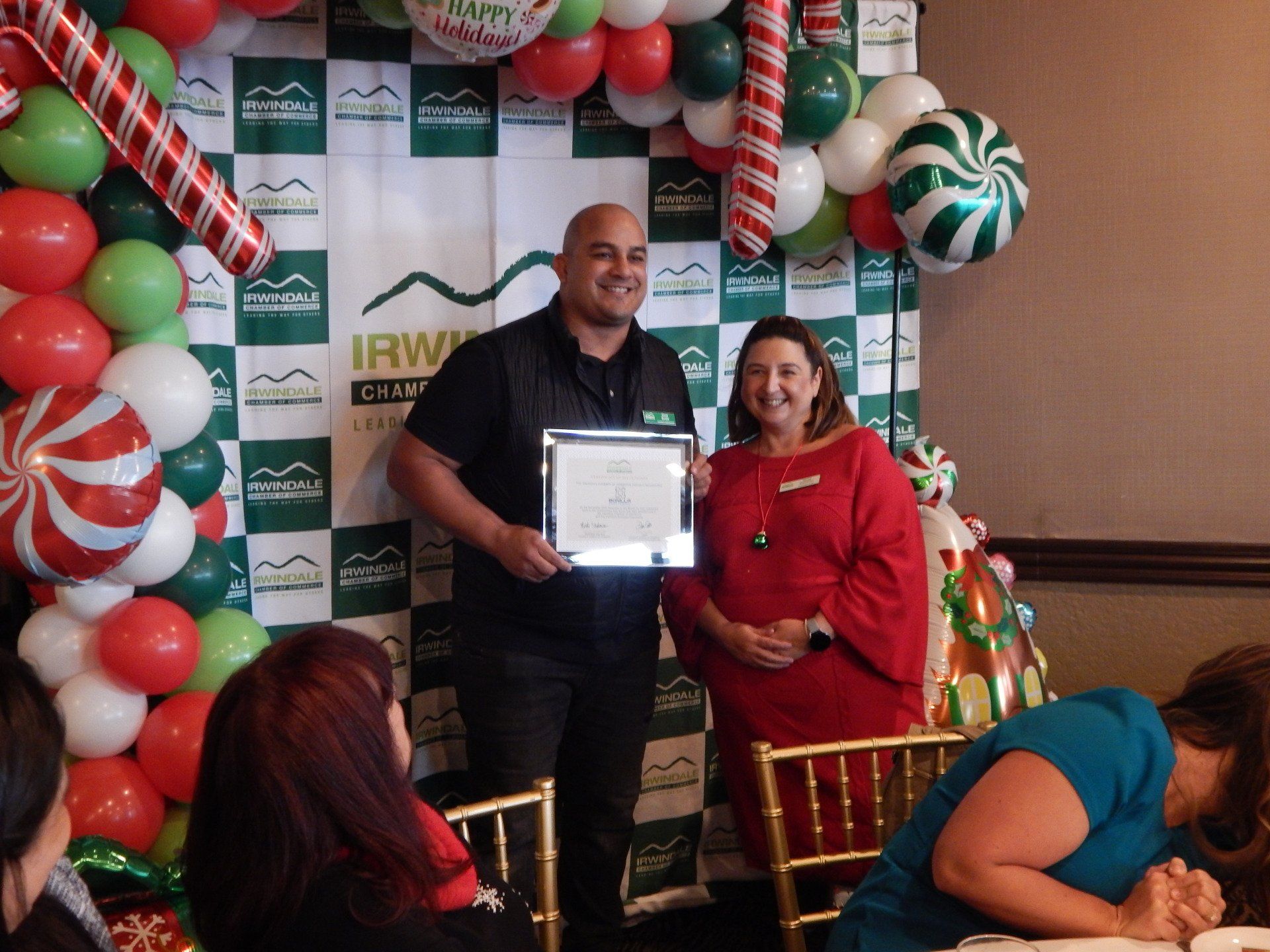 A man is holding a certificate in front of a christmas backdrop