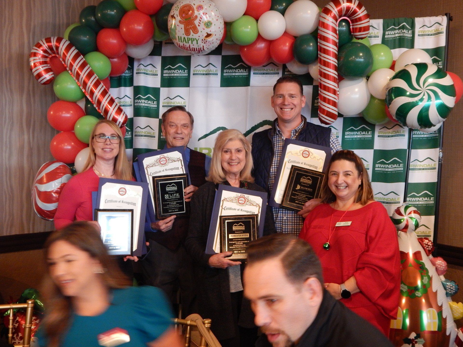 A group of people holding awards in front of balloons and candy canes
