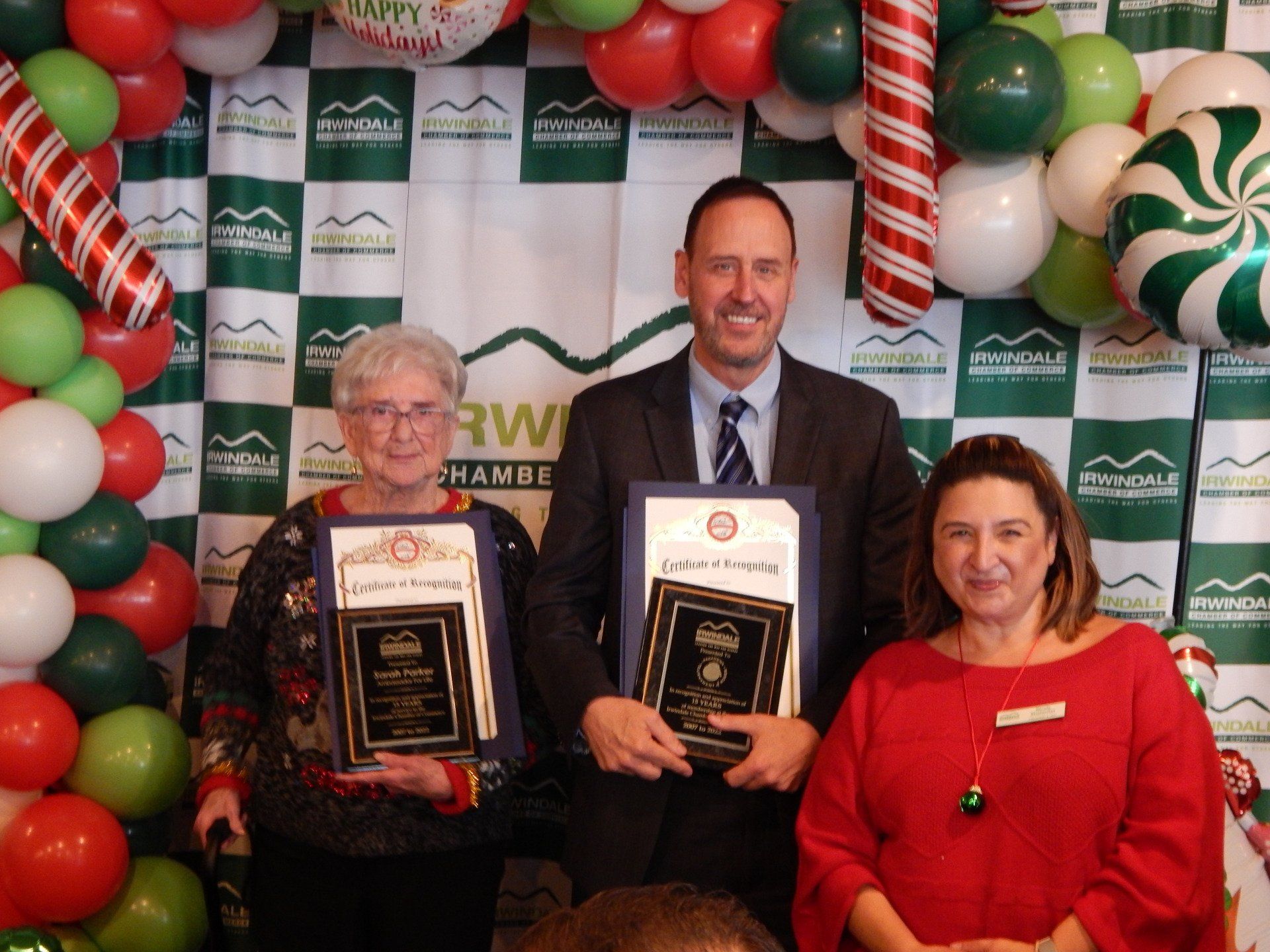 A man and two women holding awards in front of balloons