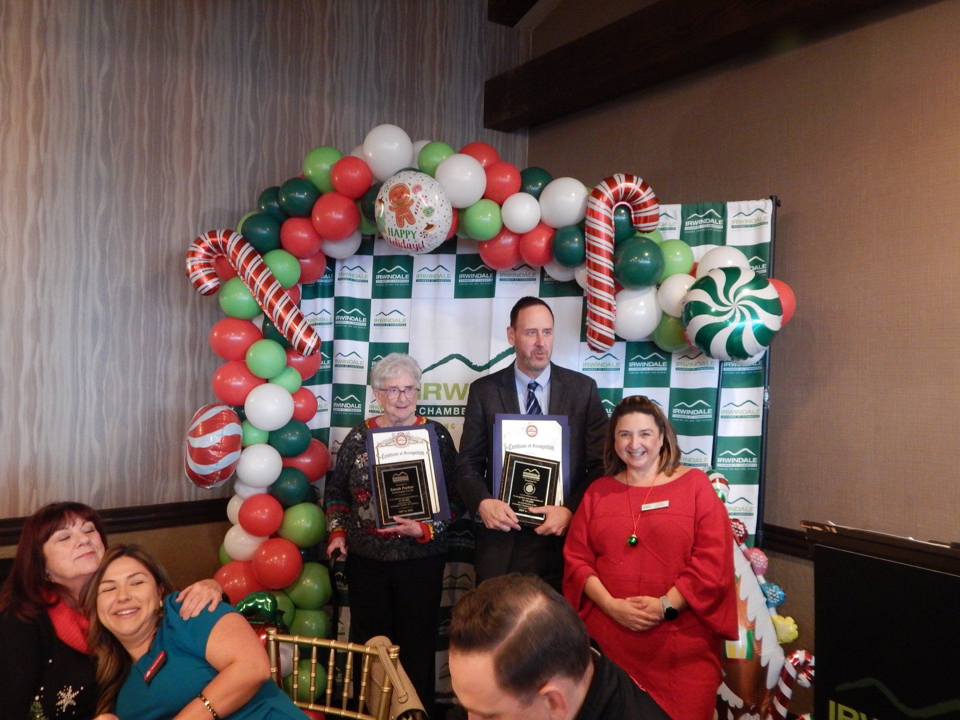 A group of people are posing for a picture in front of a balloon arch.