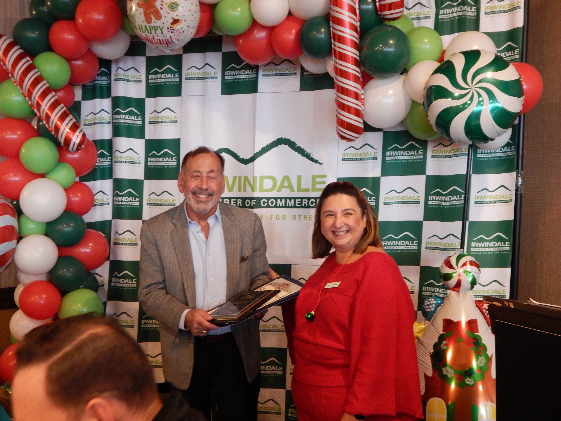 A man and a woman are standing in front of a christmas backdrop.