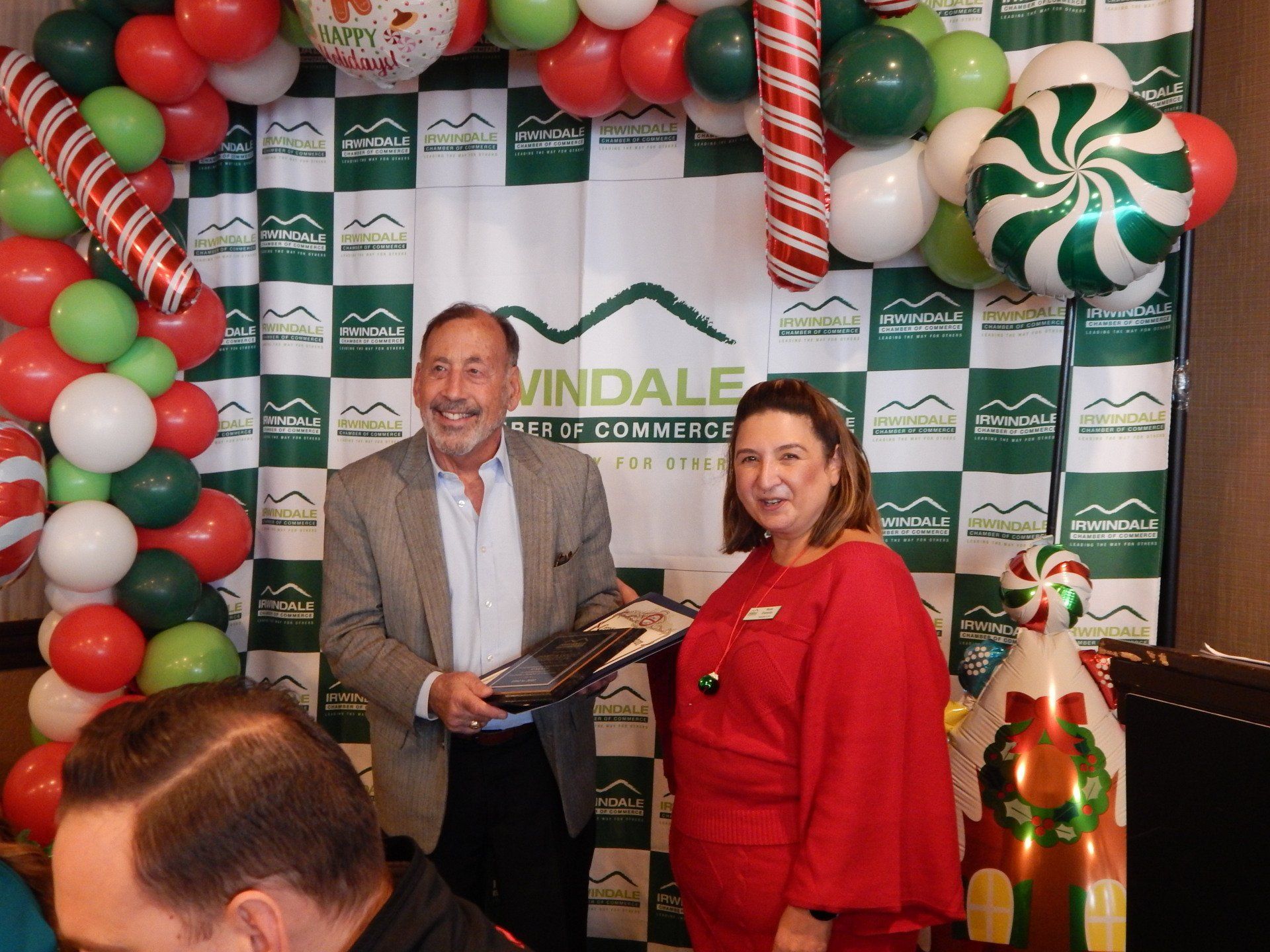 A man and woman are standing in front of a wall with balloons and candy canes.
