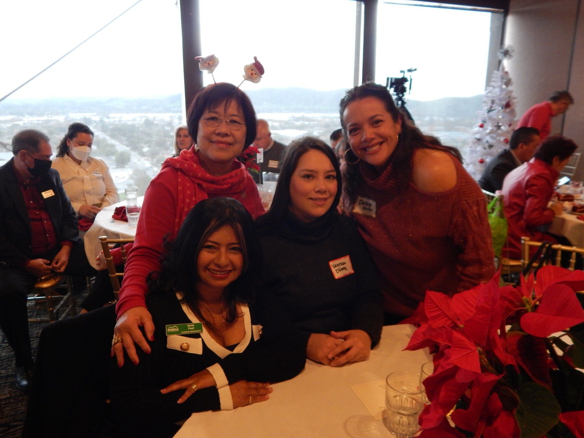 A group of women are posing for a picture while sitting at a table.