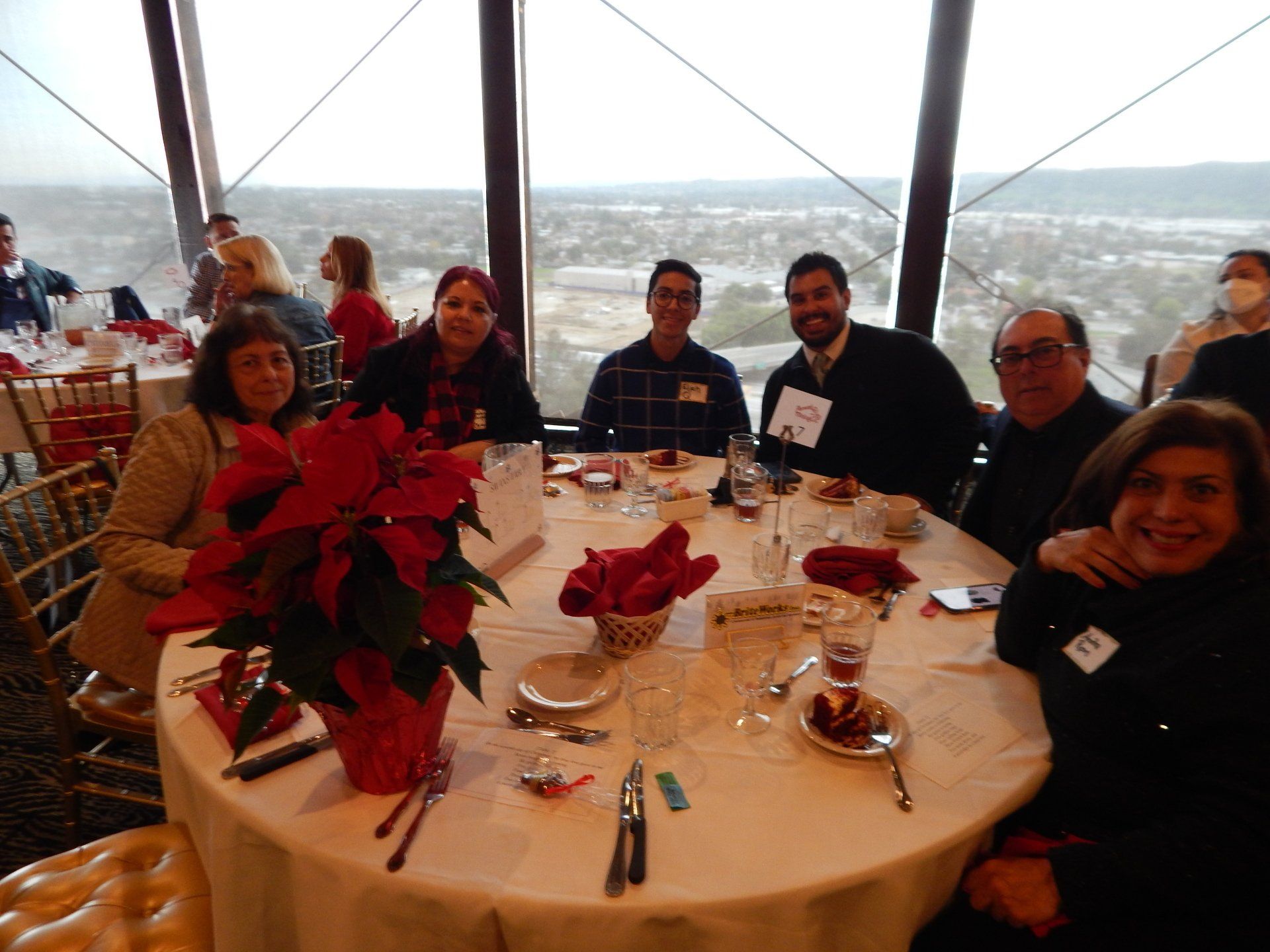 A group of people are sitting at a table with a poinsettia in front of them.