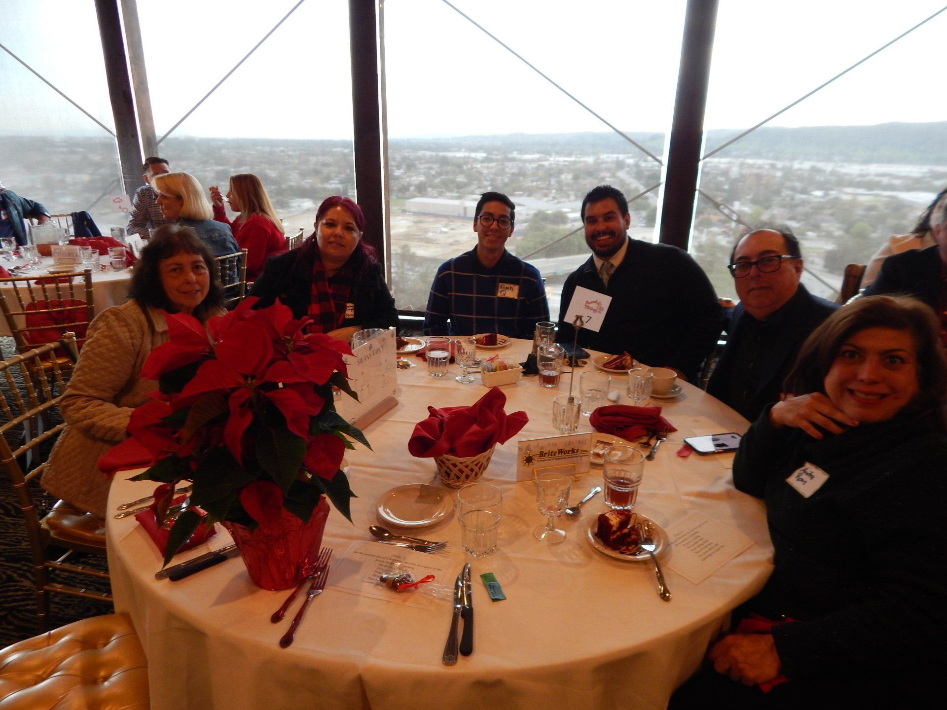 A group of people are sitting at a table with a poinsettia in front of them.