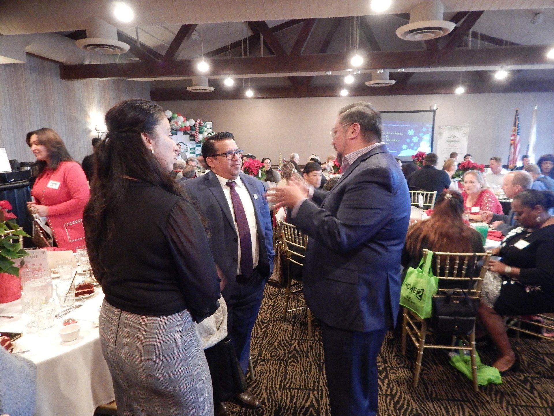 A group of people are standing in a room talking to each other.