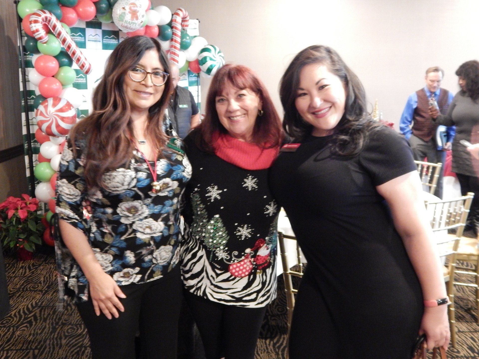 Three women posing for a picture with balloons in the background