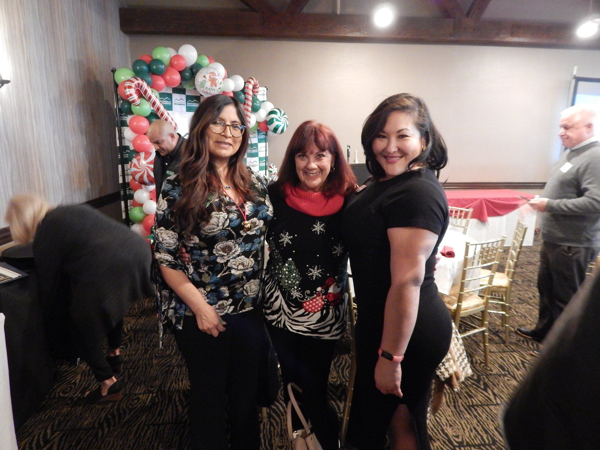 Three women are posing for a picture in a room with balloons in the background.
