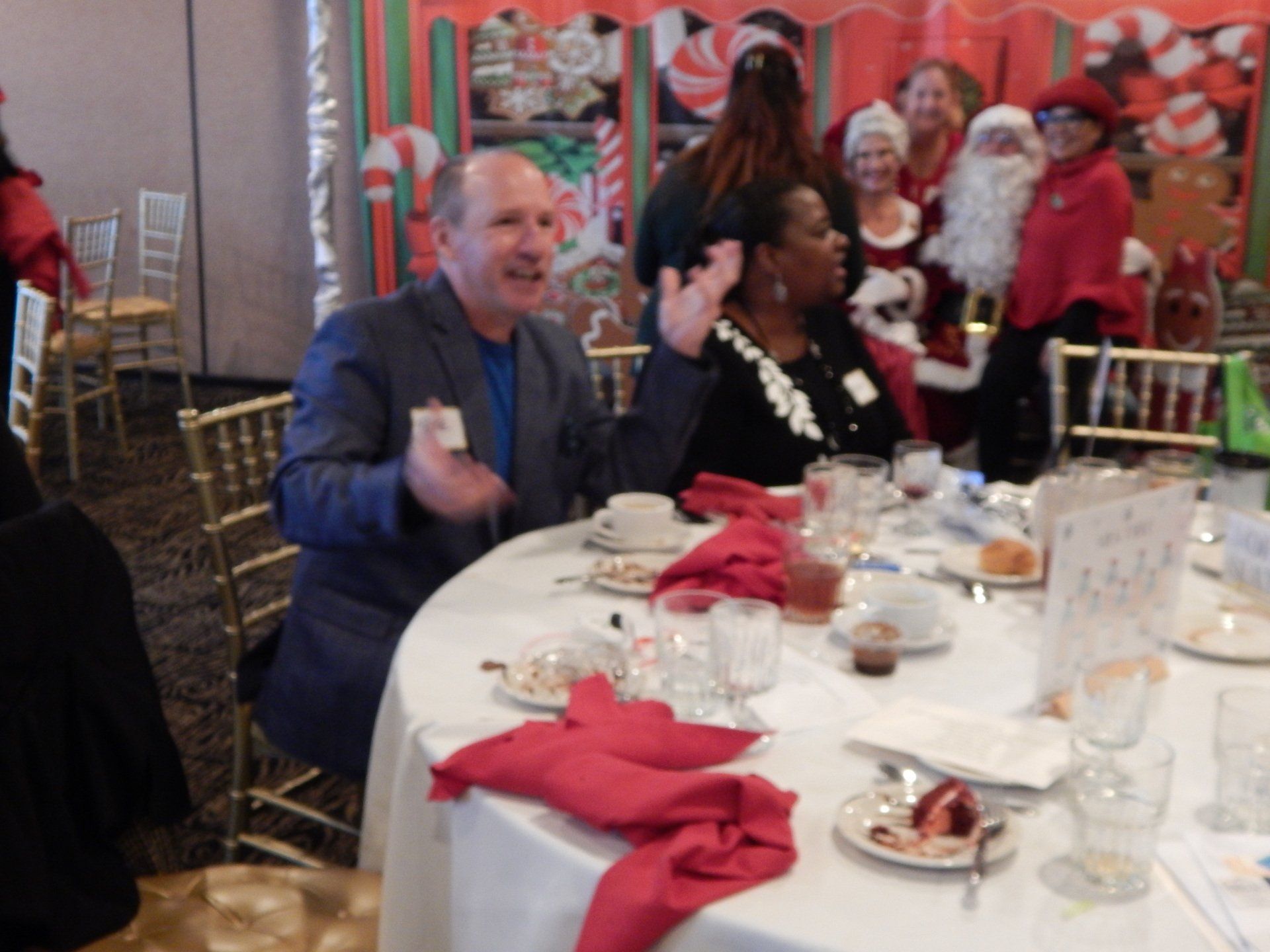 A group of people are sitting at a table with santa claus in the background