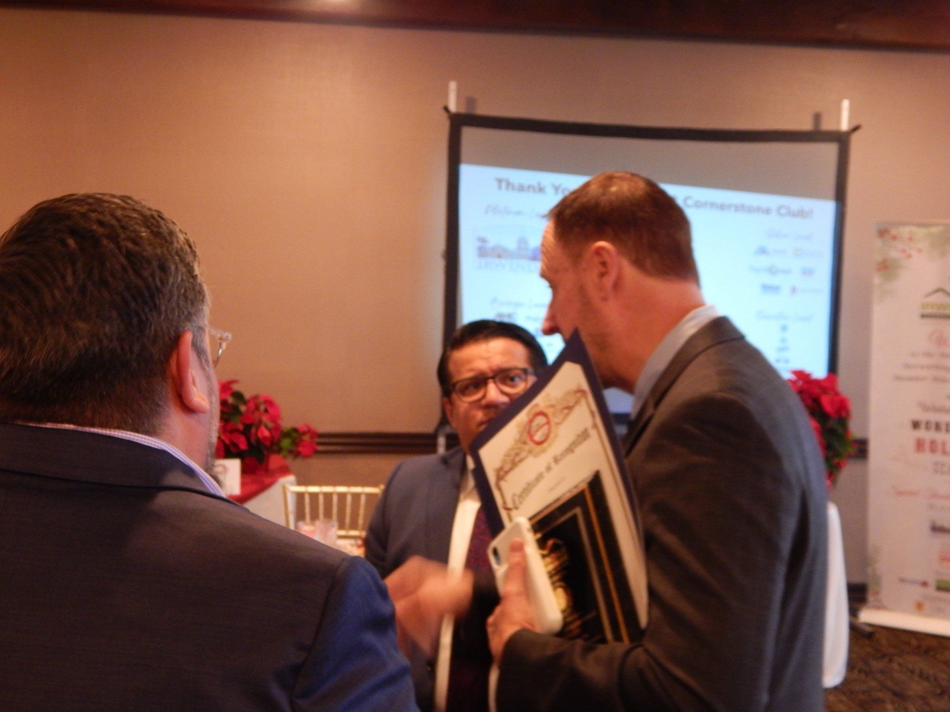 A group of men are standing in front of a screen that says thank you
