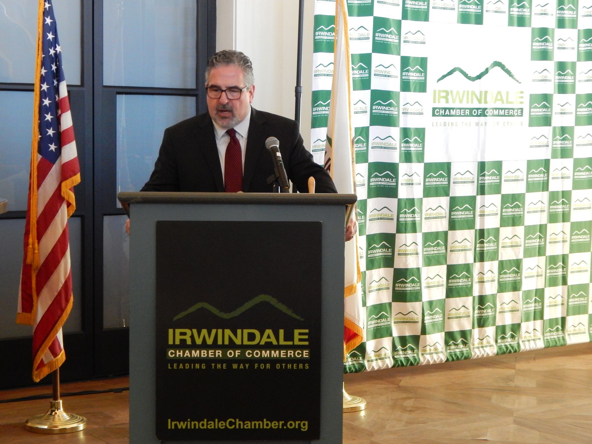 A man stands behind a podium that says irwindale chamber of commerce