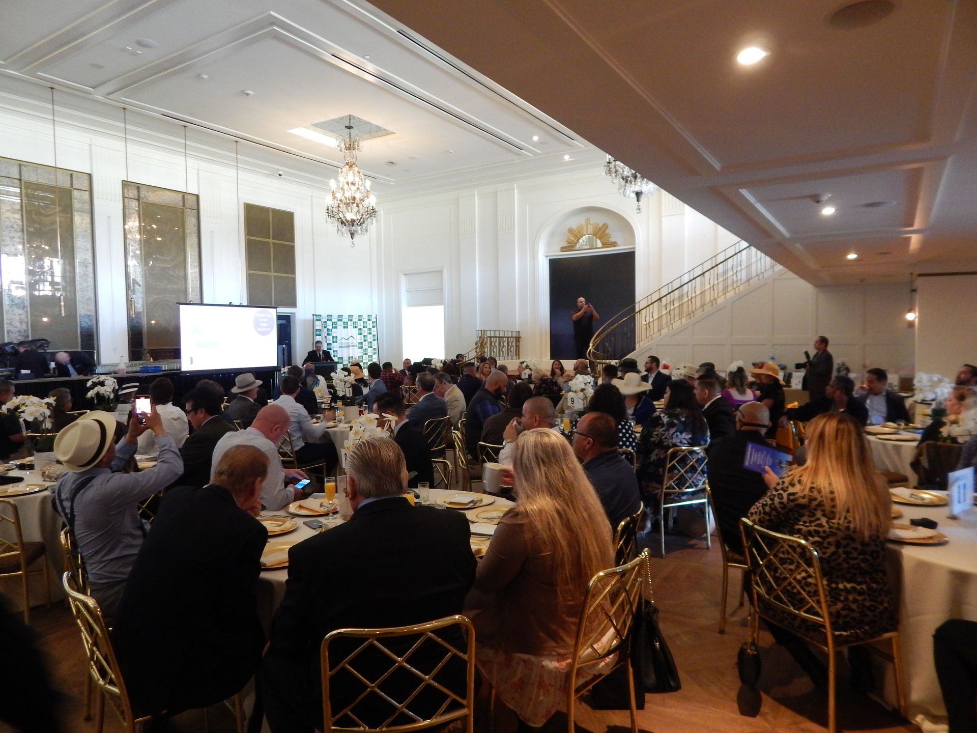 A large group of people are sitting at tables in a large room.