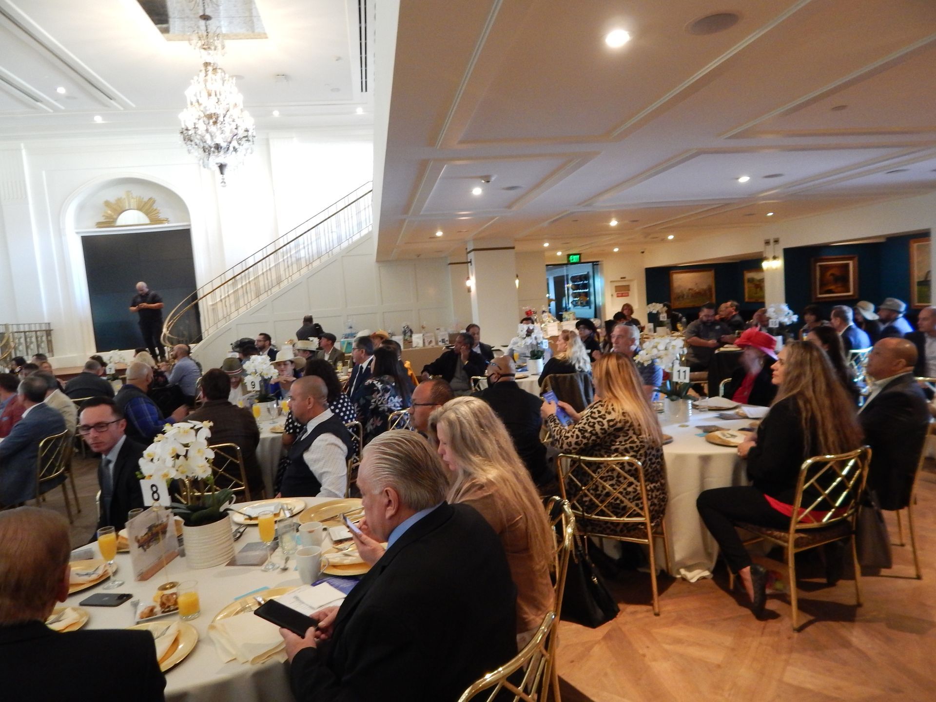 A large group of people are sitting at tables in a large room.