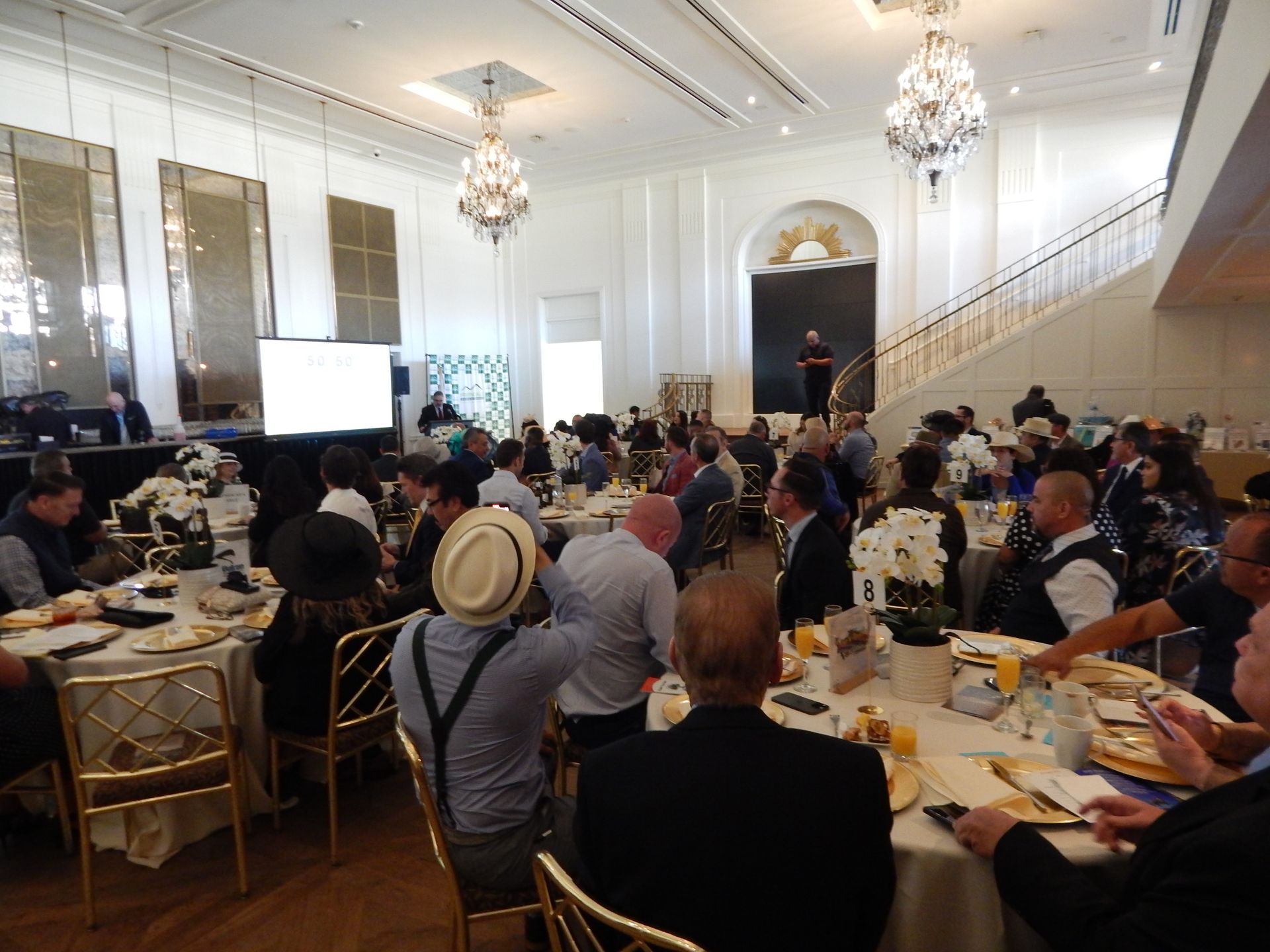 A large group of people are sitting at tables in a large room.