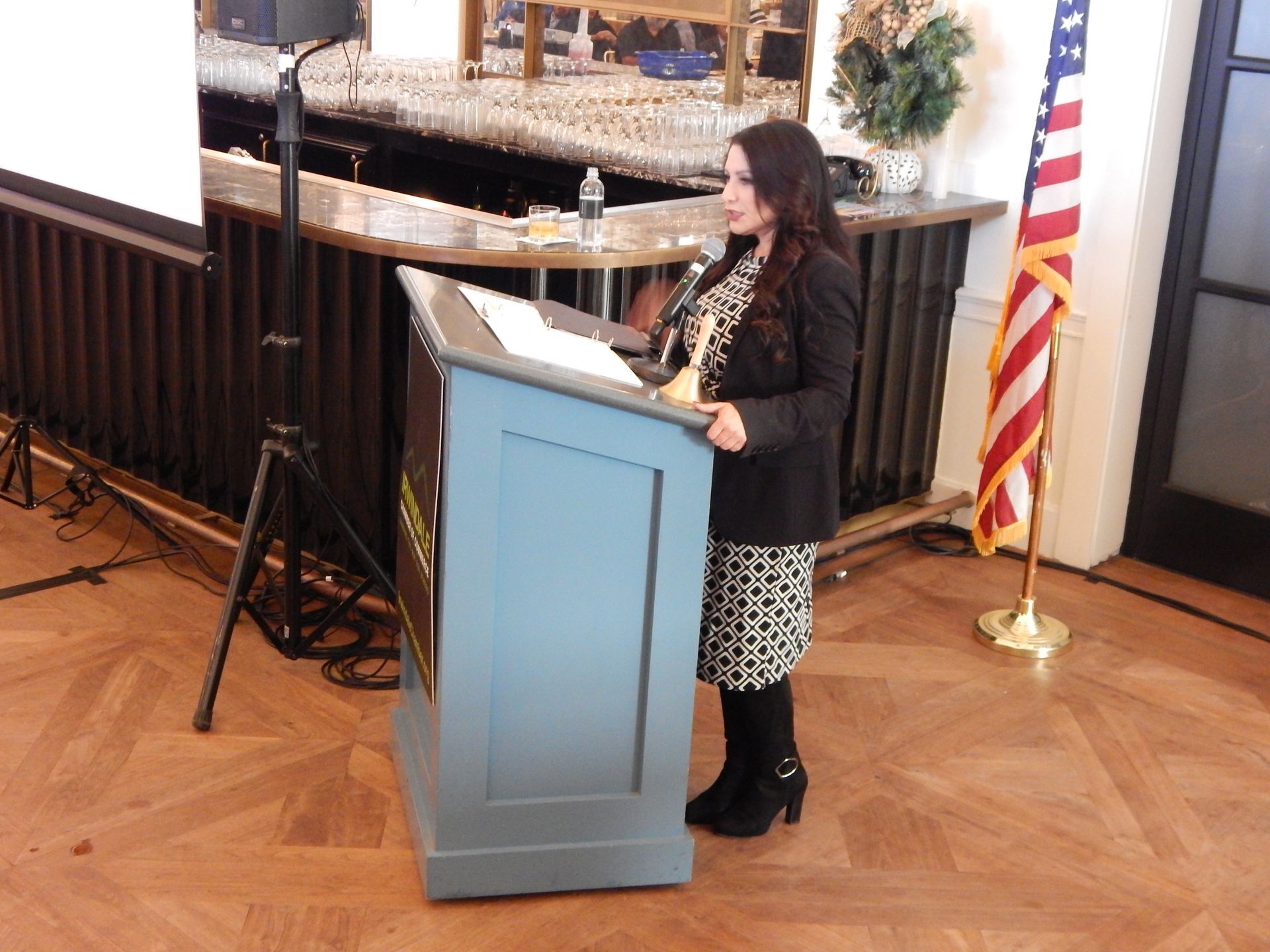 A woman is standing at a podium with an american flag in the background.