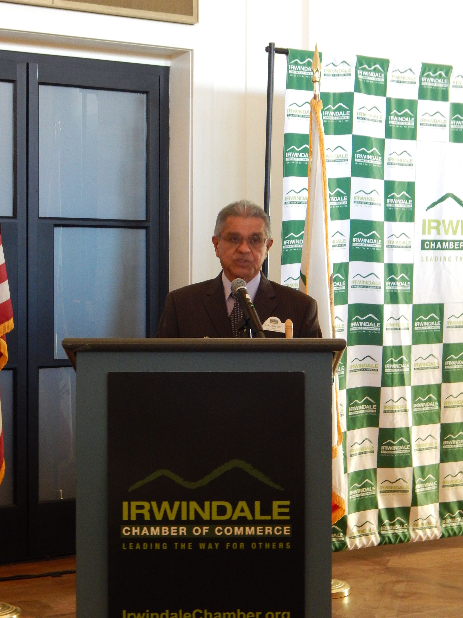 A man stands behind a podium that says irwindale chamber of commerce