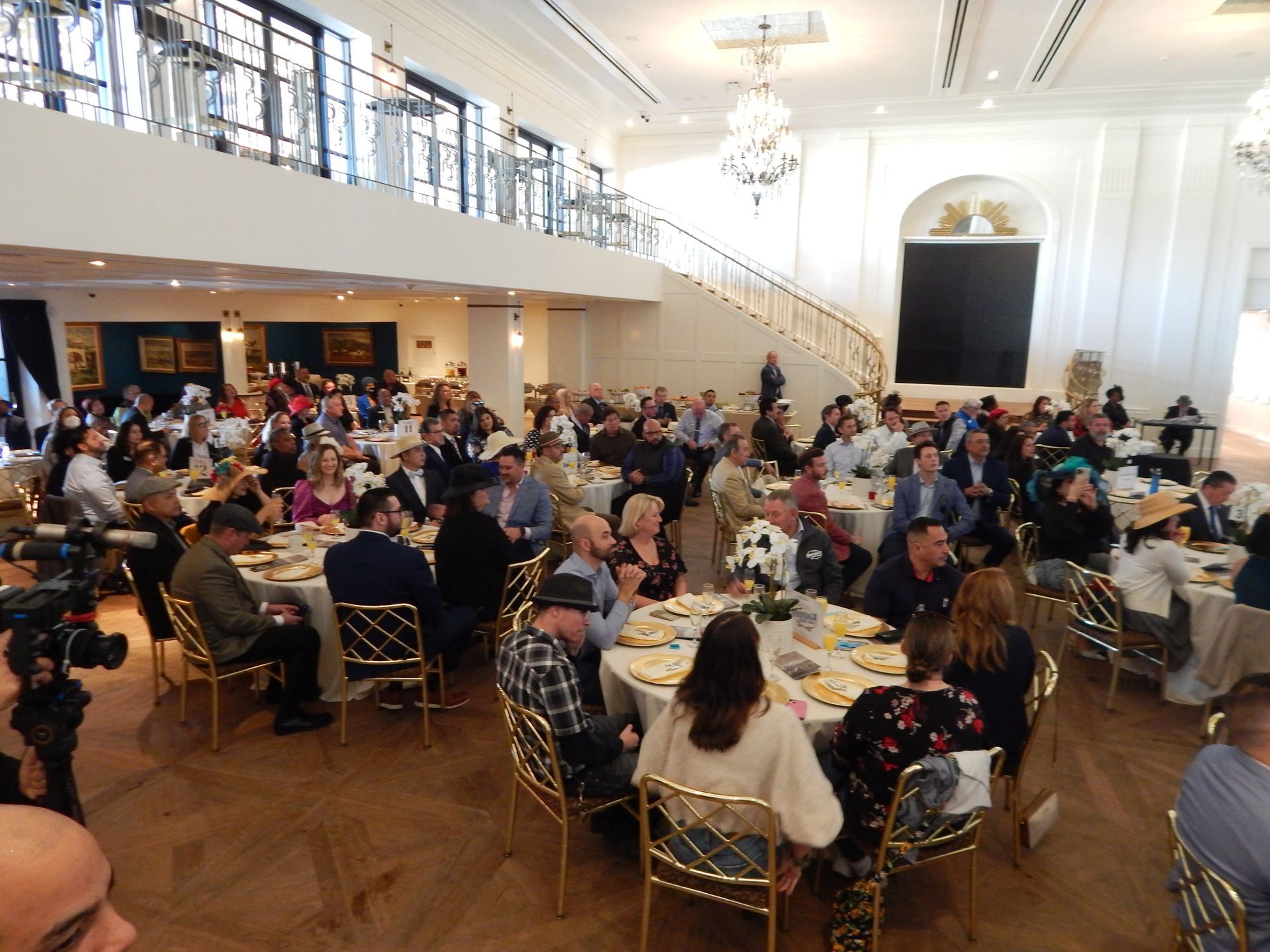 A large group of people are sitting at tables in a large room.