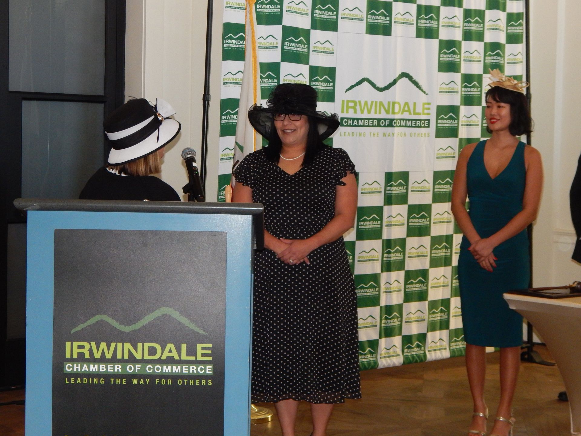 Three women standing in front of a podium that says irwindale chamber of commerce