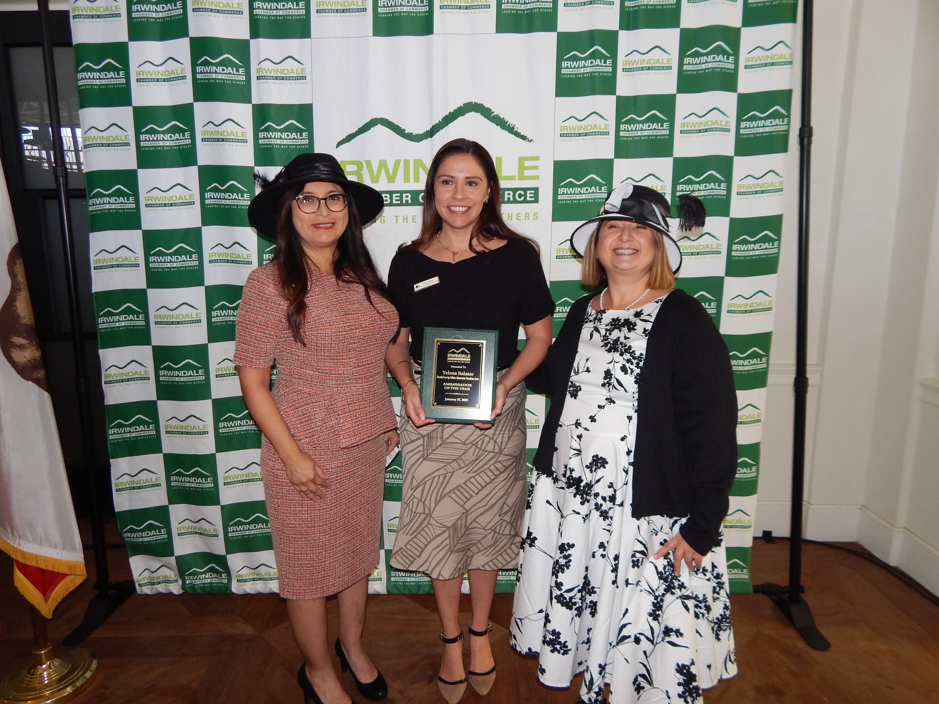 Three women standing in front of a green and white checkered backdrop
