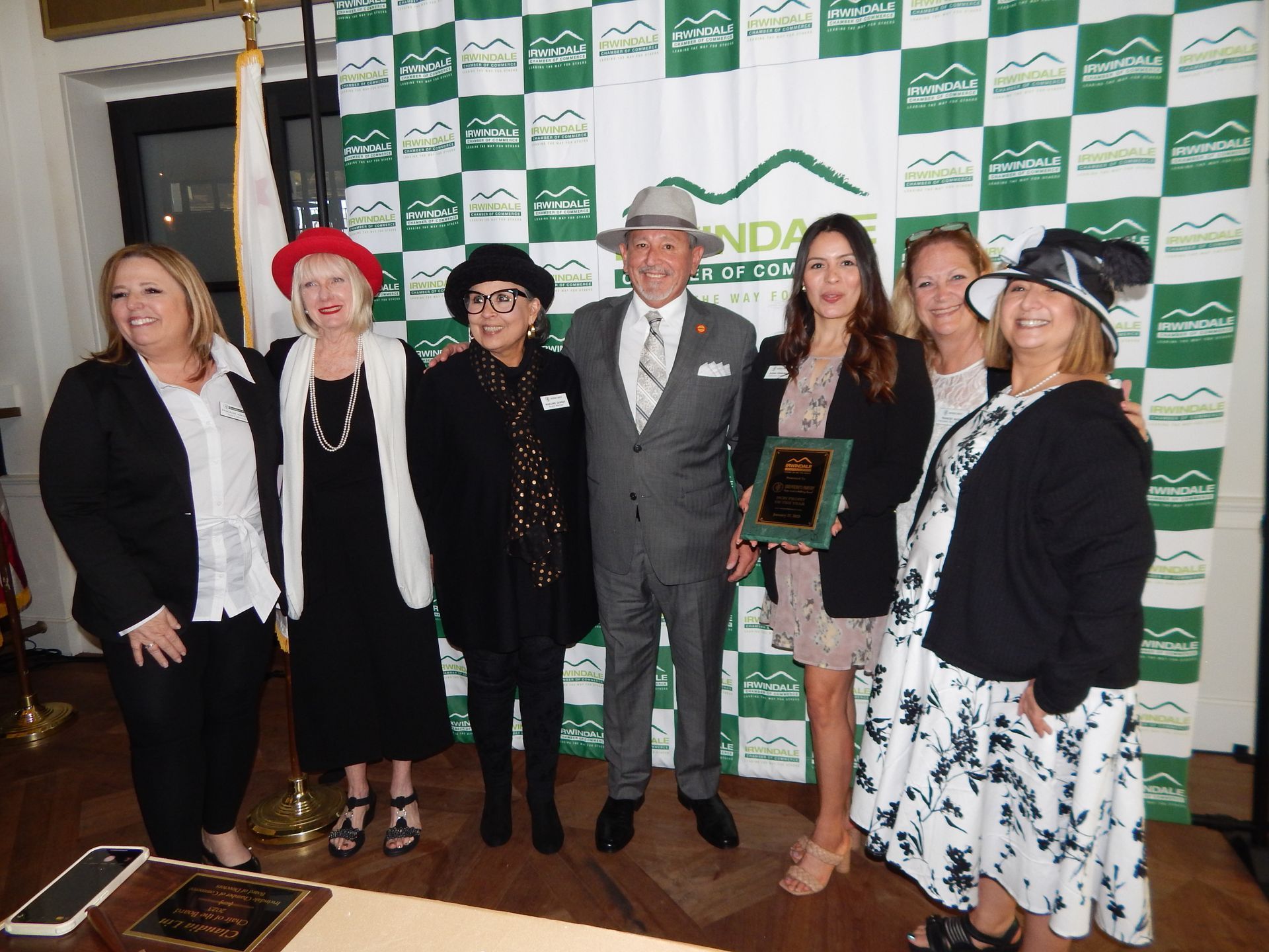 A group of people posing for a picture with a man in a suit holding a plaque.