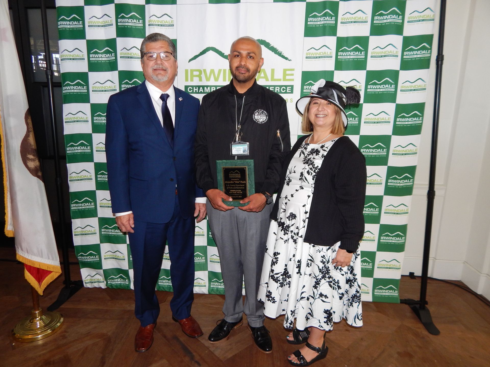 Three people standing in front of a wall that says irwinale