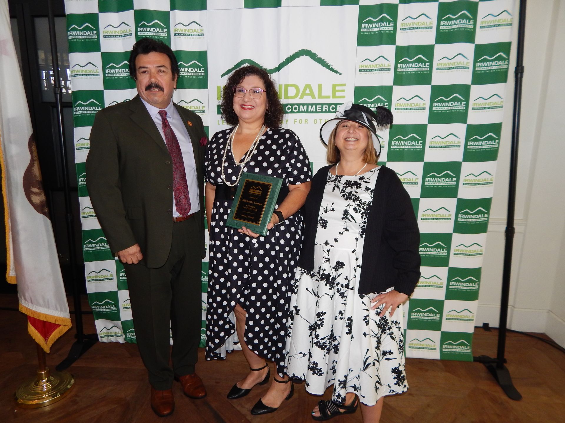 Three people standing in front of a wall that says dale