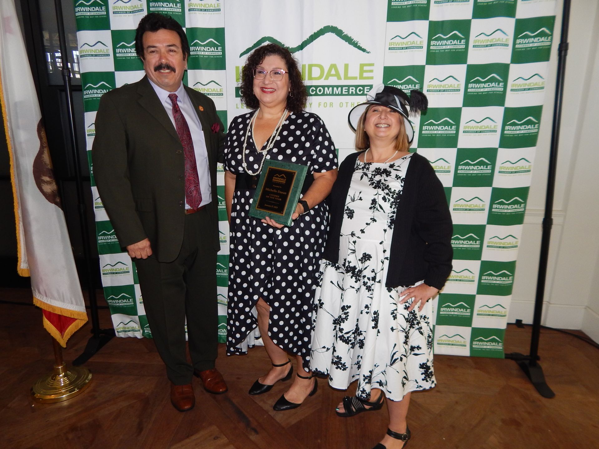 A man and two women pose in front of a wall that says dale