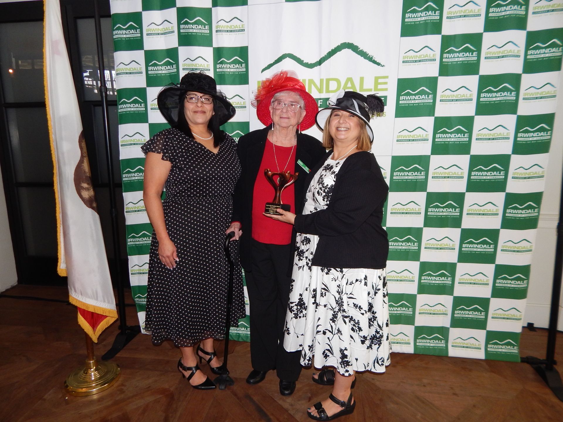 Three women are posing for a picture in front of a wall that says landale