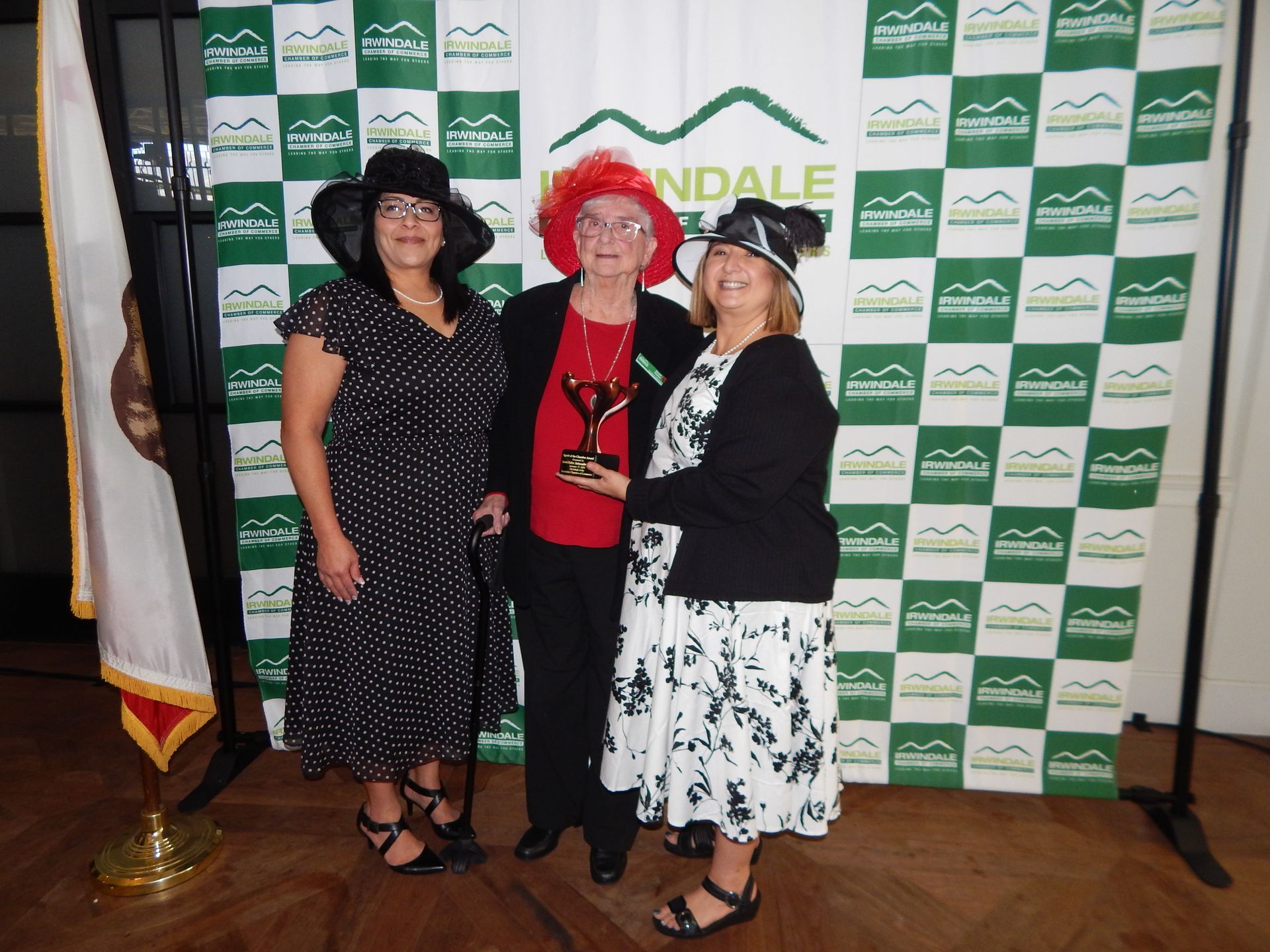 Three women are posing for a picture in front of a wall that says ndale