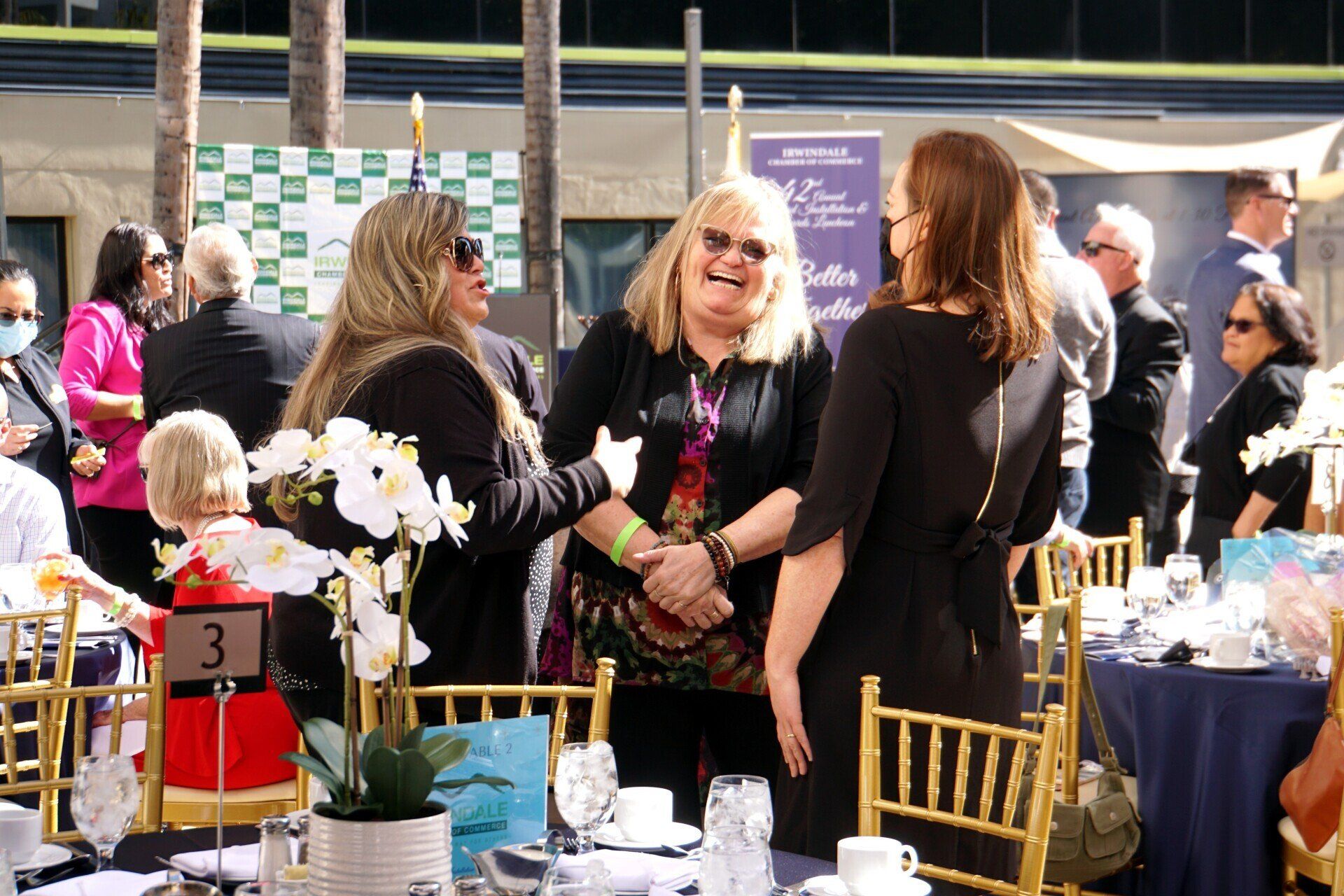 A group of women are sitting at tables talking to each other.